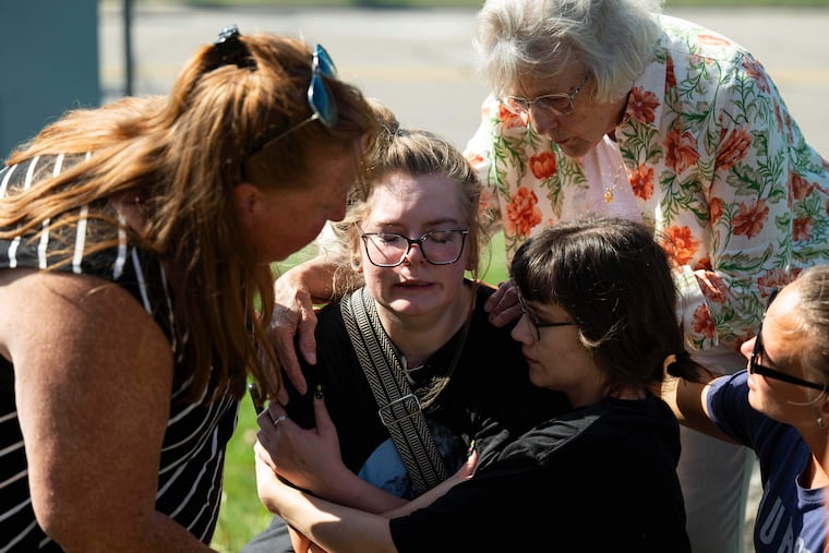 Joanne Green of Fenton (top right) and McKenna Harrington (second from right) comfort Katelyn Kruse (center) after Kruse was present at the scene of a shooting and structure fire at The Church of Jesus Christ of Latter-day Saints in Grand Blanc, Mich., on Sunday, Sept. 28.