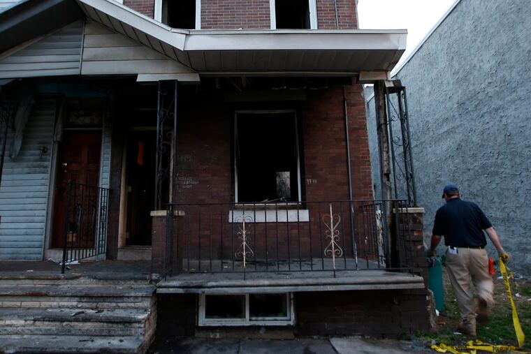 An L & I worker takes down crime scene tape after a hit-and-run and a house fire on the 4400 block of Wingohocking St., in the Nicetown neighborhood of Philadelphia on April 17, 2015. ( Yong Kim / Staff Photographer )