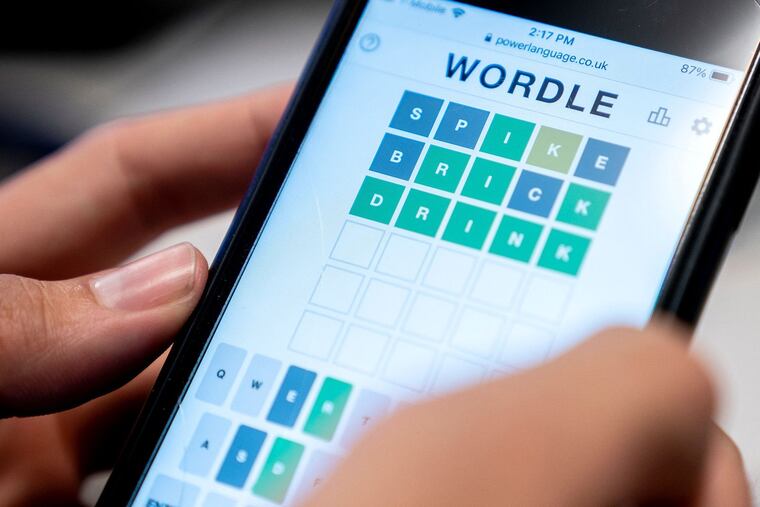 This photo illustration shows a person playing the online word game "Wordle" on a mobile phone.