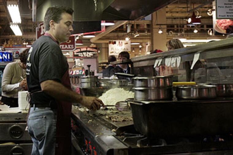 Rick Olivieri, owner of Rick's steaks prepares cheese-steak sandwiches at the Reading Terminal Wednesday at noon. (Bonnie Weller / Staff Photographer)