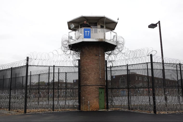 A solitary corrections officer looks out from a tower at one corner of the state prison in Camp Hill, Pa.