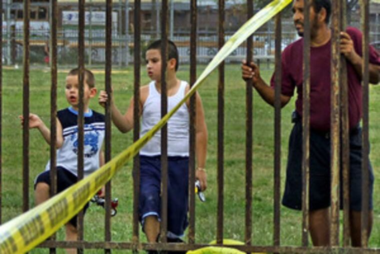 Onlookers yesterday watch cops probe a hit-and-run accident that hurt two kids on Torresdale Ave.