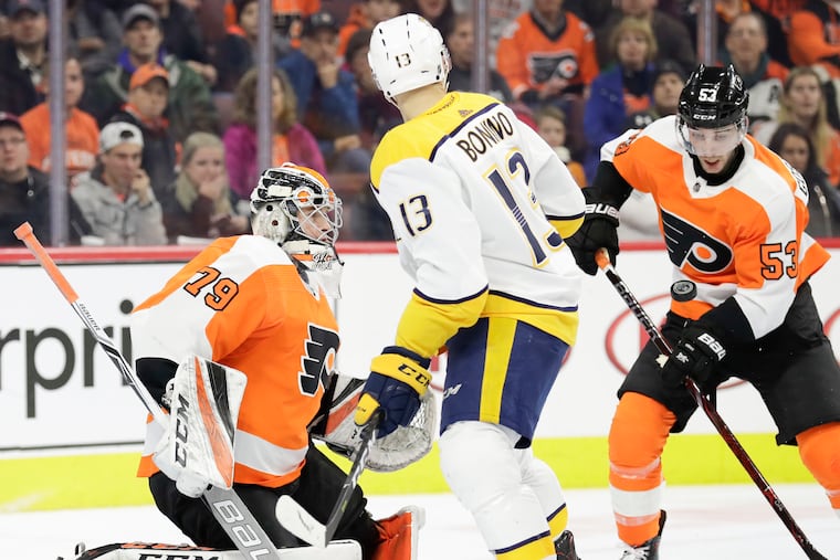 Flyers defenseman Shayne Gostisbehere watches the puck with goaltender Carter Hart against Nashville Predators center Nick Bonino during the second-period Thursday.
