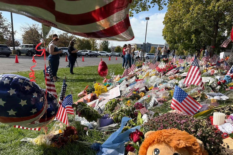 People bring flowers and write messages in chalk at a memorial for Charlie Kirk at Utah Valley University, on Monday, Sept. 15, 2025, in Orem, Utah. (AP Photo/Jesse Bedayn)