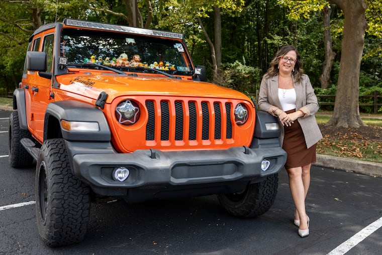 Jennifer Senzick, owner of an orange 2018 Jeep Wrangler JL, poses for a photo with her car in Horsham.