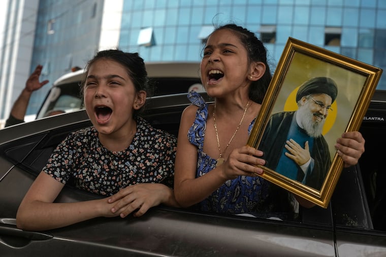 Two girls chant slogans as one holds an image of the late Hezbollah leader Hassan Nasrallah in Dahiyeh, Beirut's southern suburbs, Lebanon, Friday, April 17, 2026, following a ceasefire between Israel and Hezbollah.