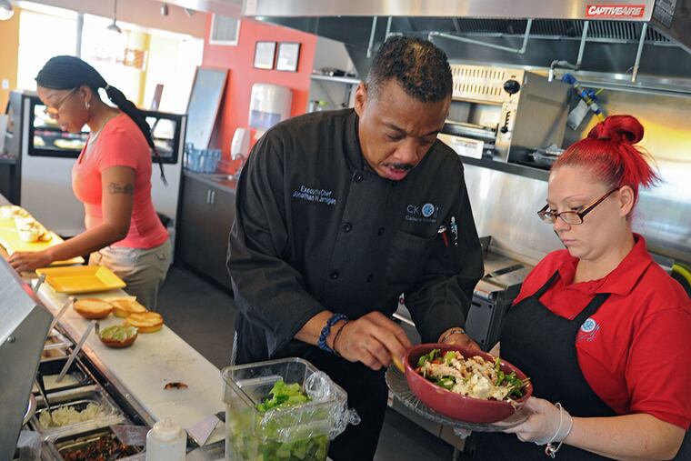Jonathan Jernigan, CK's executive chef, puts the finishing touches on a salad prepared by Victoria Romano. His secret to the cafe's offerings? "Big, bold flavors. Things that make your mouth go crazy." CLEM MURRAY / Staff Photographer