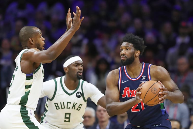 Philadelphia 76ers center Joel Embiid (21) looks to pass the ball around Milwaukee Bucks forward Khris Middleton (22) and Milwaukee Bucks center Bobby Portis (9) during a game at the Wells Fargo Center in Philadelphia on Tuesday, March 29, 2022.