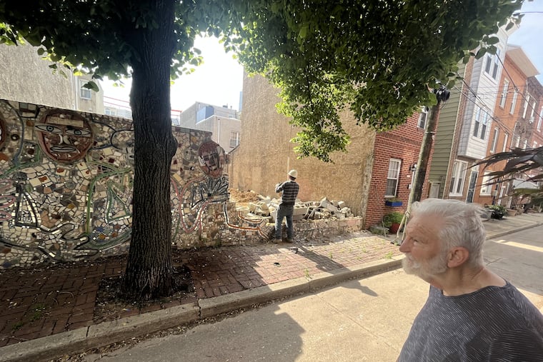 Artist Isaiah Zagar watches the demolition Friday of a mosaic he made on South Mildred Street 30 years ago.