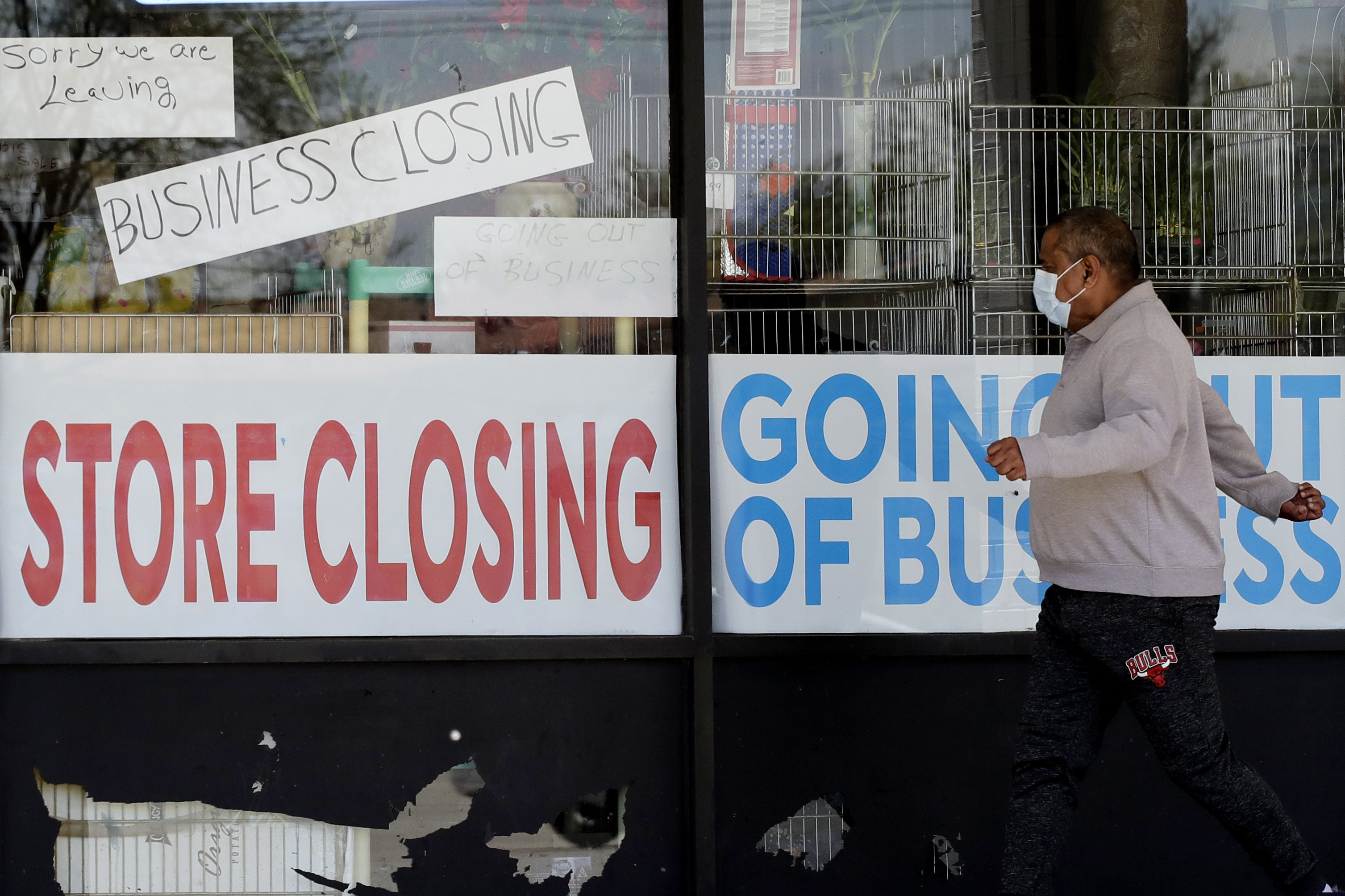 A man looks at signs of a closed store due to COVID-19 in Niles, Ill.