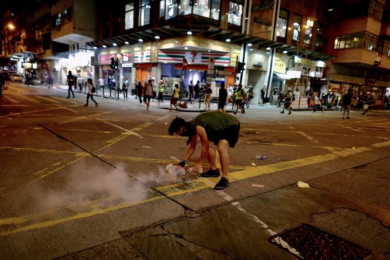 A protester uses a plate to cover a tear gas during clashes with policemen near the Shum Shui Po police station in Hong Kong on Wednesday, Aug. 14, 2019.