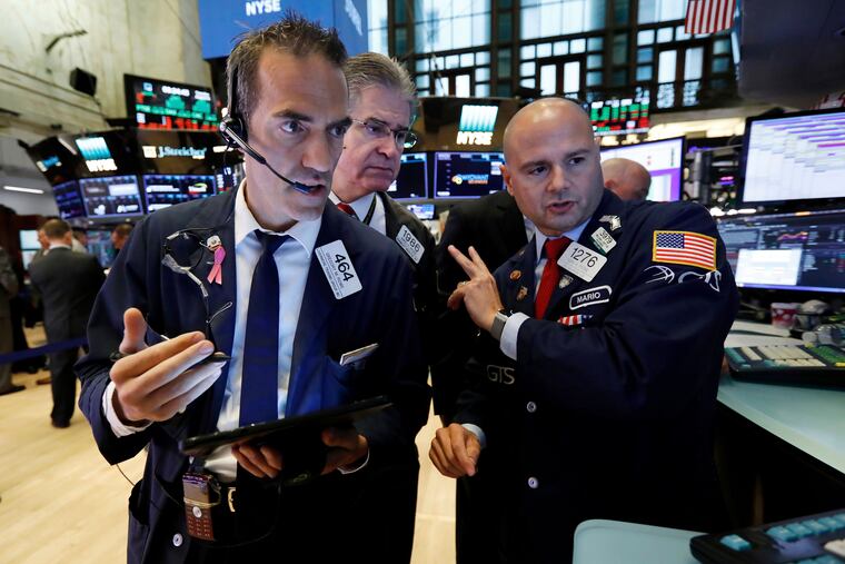 Traders Gregory Rowe, left, and Daniel Kryger, center, work with specialist Mario Picone on the floor of the New York Stock Exchange, Tuesday, Aug. 6, 2019.