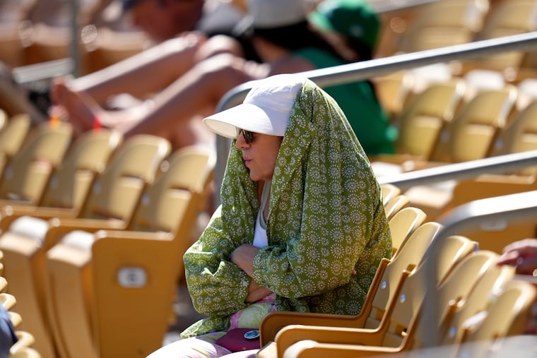 A baseball fan tries to shield from the sun during the fourth inning of a spring training baseball game between the Chicago White Sox and the Athletics, March 17, 2026, in Phoenix.