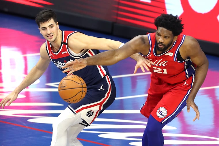 Joel Embiid, right, and Deni Avdija go after a loose ball during the second half of Wednesday's season opener. The Sixers won 113-107.