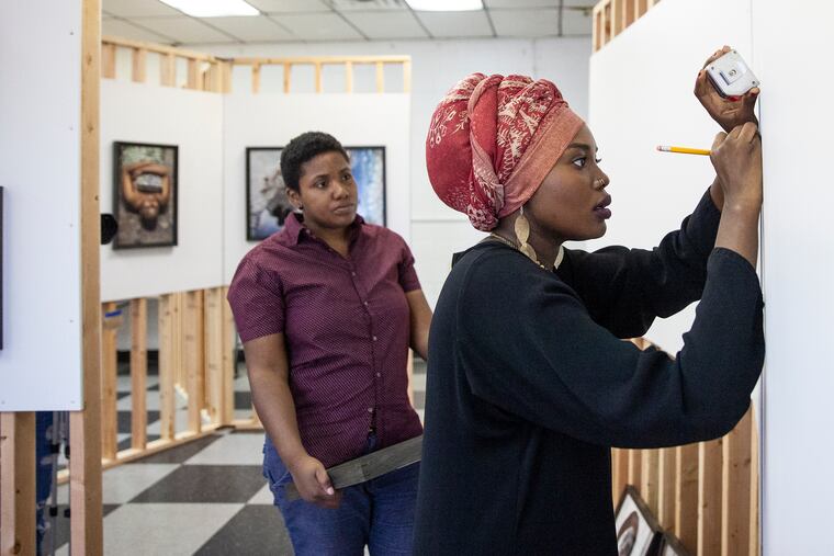 Davelle Barnes, left, helps fellow artist Afaq as she takes measurements before hanging up her art work at the Juniata Park Boys & Girls Club on Wednesday, Sept. 19, 2018. The Women's Mobile Museum is a collection of work by a group of artists who are women of color, and whose work tries to answer the question, "Who is art for?" The exhibit will be around Philadelphia until March 2019.