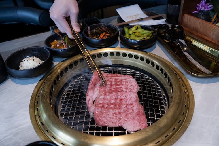 Server Gina Lee prepares Japanese Wagyu barbecue tableside at OGYU Japanese BBQ on Tuesday, July 7, 2026, in Ardmore. The newly opened restaurant offers a modern Japanese steakhouse experience with tabletop grilling, adding to Ardmore's growing dining scene.