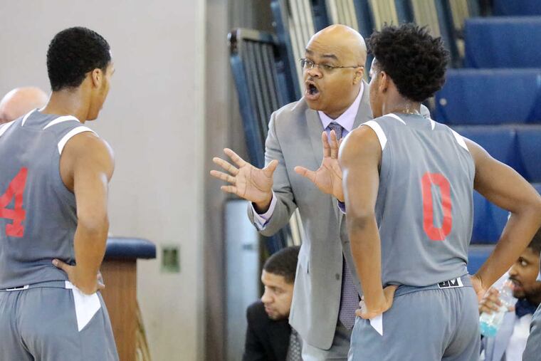 Olympus Prep coach Rob Lawton talks with players Justin Ryder (4) and Juanye Colon (0) during timeout of a game at the Seagull Classic.