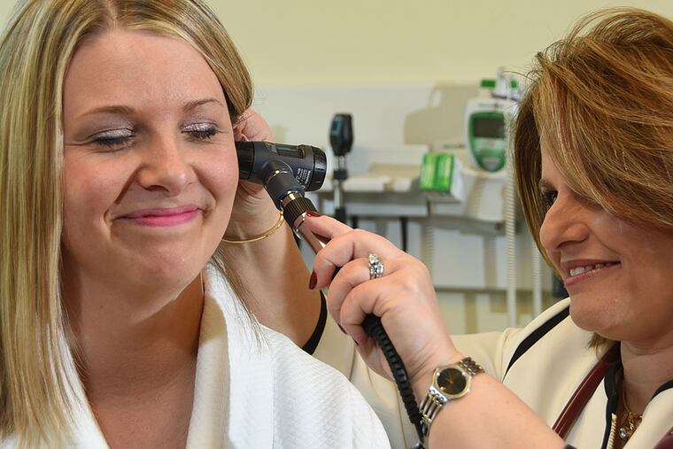 Lindsay Hannah laughs as Nermin Lazarus tickles her ear during an exam at Virtua Women's Primary Care and Wellness Center in Mount Laurel, where Lazarus is the lead physician. Above, doctor and patient consult. CURT HUDSON