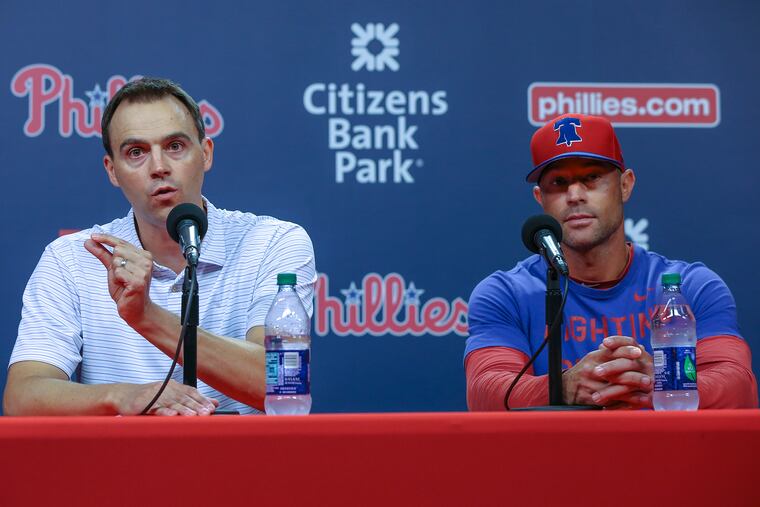 Phillies General Manager Matt Klentak left, and Manager Gabe Kapler talk to media about firing their hitting coach John Mallee and hiring Charlie Manuel to replace him, at Citizens Bank Park in Philadelphia. Klentak says being two game out of a wild card the team "is this close to the playoffs" Tuesday, August 13, 2019