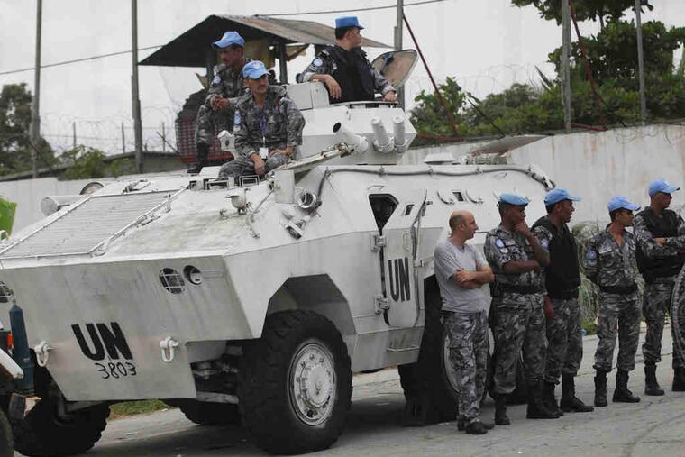 United Nations peacekeeping forces wait outside U.N. headquarters Monday in Abidjan, Ivory Coast. A Security Council resolution extends the force's mandate in the country to June 30.