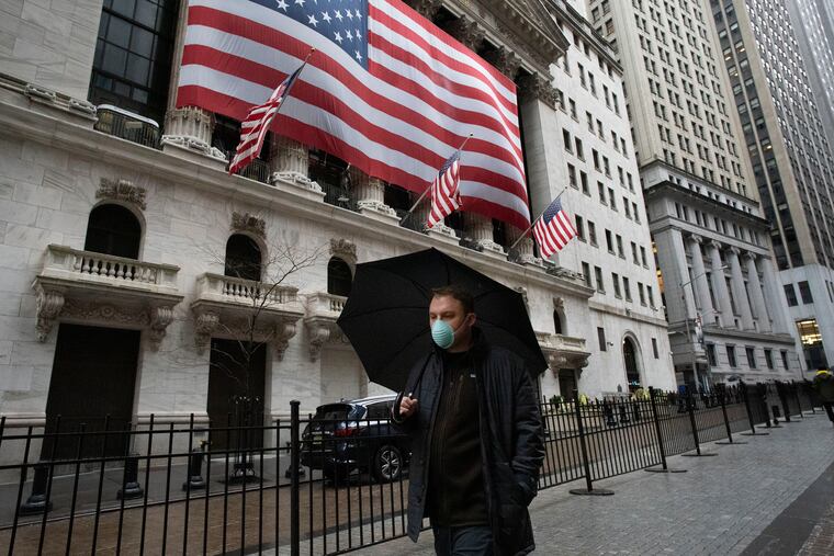A man wearing a mask walks by the New York Stock Exchange, Tuesday, March 17, 2020. Share prices are volatile after a brutal sell-off that gave the U.S. stock market its worst loss in more than three decades. Markets in Europe lost early gains and were trading lower on Tuesday.