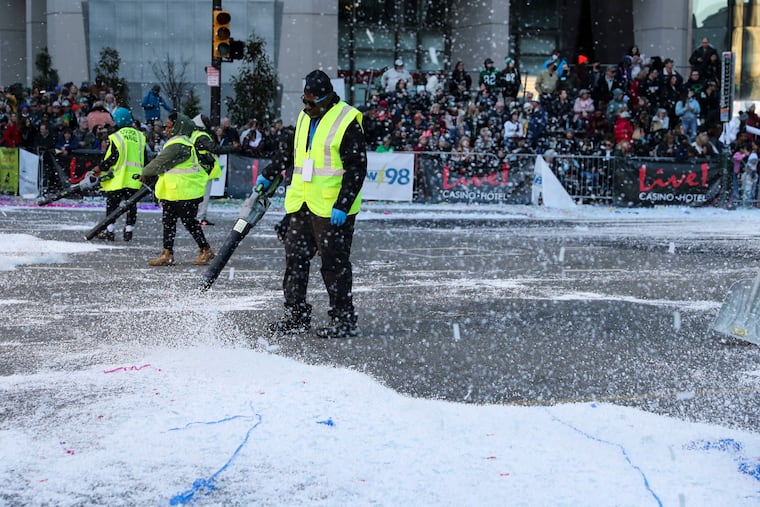 Workers clean up fake snow after the Ferko String Band performed “Freeze The Day!” during the Mummers Parade. So far, the region has been short on real snow.