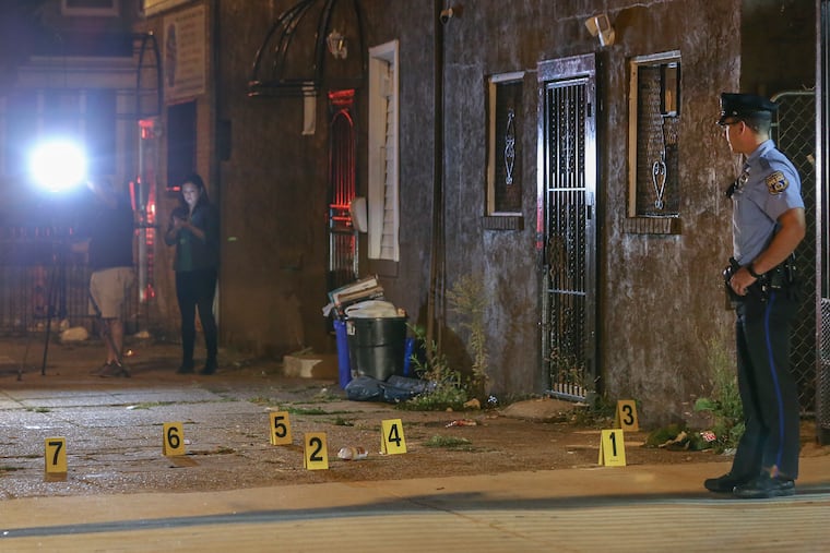 Philadelphia police officers investigate a shooting scene where a police officer was shot at on the 5900 block of Kingsessing Avenue on Tuesday.