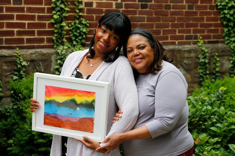 JoAnn Robinson (right) and her daughter Diamond Princess Franklin hold a gift the Double Rainbows Project presented them in memory their mother and grandmother, Ida Rebecca Robinson, who passed away from the coronavirus in April of 2020. The project has collected rainbows hand-drawn by city kids during the pandemic and is offering them to families who have lost loved ones to Covid-19.