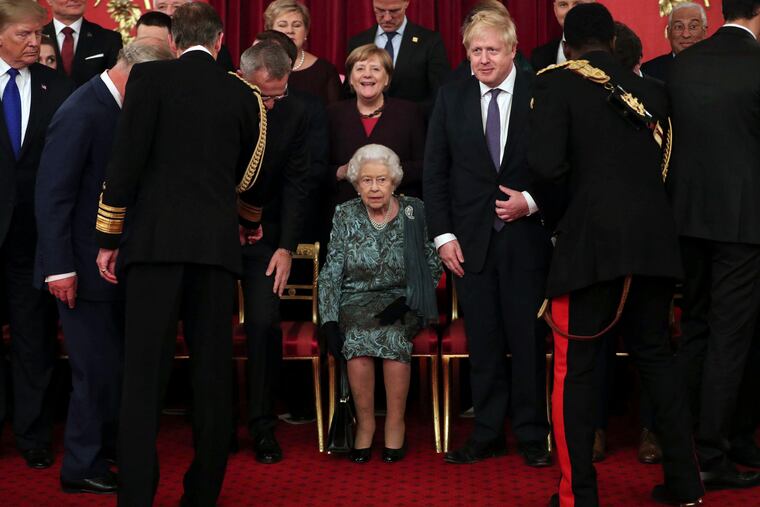 Britain's Queen Elizabeth II, centre, takes her seat with Britain's Prime Minister Boris Johnson and Chancellor of Germany Angela Merkel, behind, before a formal group photo during a formal reception for the heads of the NATO countries, at Buckingham palace in London Tuesday Dec. 3, 2019. Leaders from across the 29-member trans-Atlantic alliance are gathered in London to mark the 70th anniversary of NATO. (Yui Mok/Pool via AP)