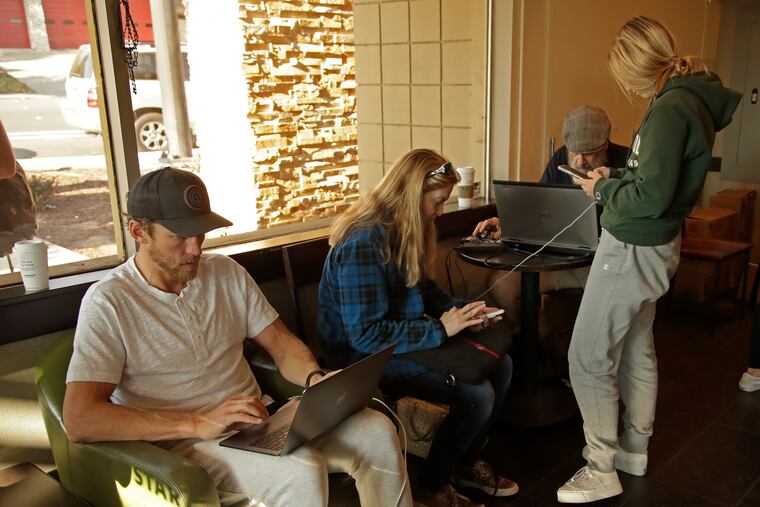Customers charge their electronic devices at Starbuck's coffee shop on Monday, Oct. 28, 2019, in Lafayette, Calif. A large part of Lafayette has been without power. PG&E said Monday its power lines may have started two wildfires over the weekend in the San Francisco Bay Area despite widespread blackouts meant to prevent fires from igniting during dangerously windy weather.