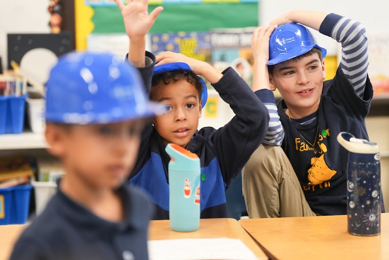 Students Landon Watkins, left, and Leo Horn, right, try on hard hats at Fanny Jackson Coppin School, in South Philadelphia.