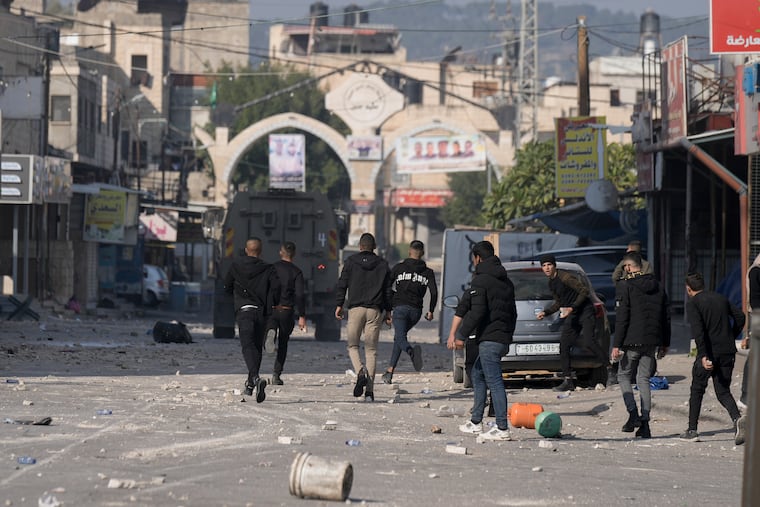Palestinians clash with Israeli forces following an army raid in the West Bank city of Jenin, Thursday, Jan. 26, 2023.
