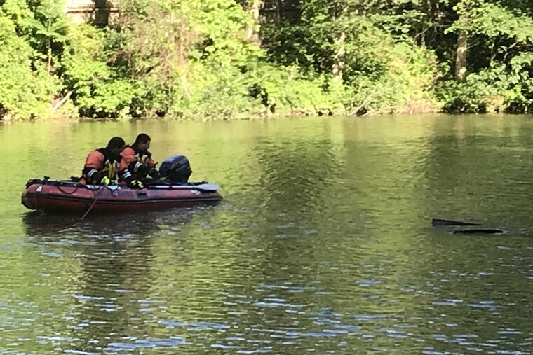 Emergency responders investigate the water around the roof of a car that crashed into a pond in Upper Merion on Tuesday.