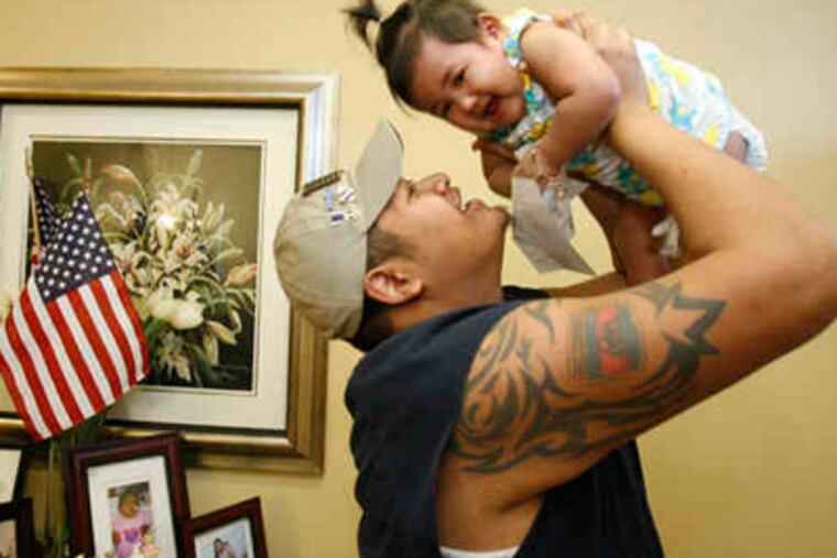 Pisey Tan lifts his daughter, Alyssa, as they play in their Woodlyn home. Tan, medically retired from the Army, lost both legs when a bomb exploded under his military vehicle in Iraq. (Charles Fox / Staff Photographer)