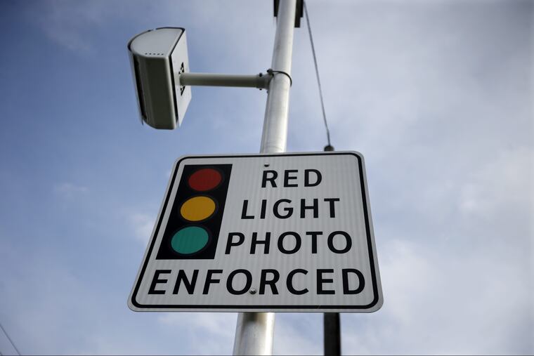 A red light photo enforcement sign is seen below a red light camera Tuesday, Dec. 16, 2014, in Lawrence Township, N.J. It and others across the state went dark when the five-year pilot program ended later that month.