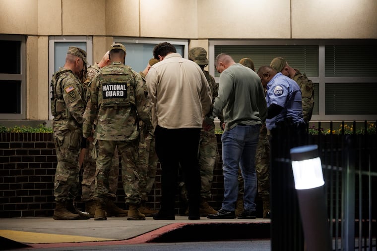 National Guard members participate in a group prayer with civilians and a security officer outside the emergency entrance to MedStar Washington Hospital Center on Wednesday after two Guard members were shot earlier in the day.
