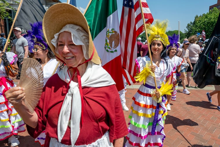 Historical interpreter for the American Revolution Diane Jost with the Sudbury (Mass.) Companies of Militia & Minute, walks with members of the Ballet Folklorico Mosaicos, dancers fro a Mexican cultural organization in Indianapolis, Ind. as groups not marching mingle on Independence Mall as Philadelphia celebrates America’s 250th birthday Friday, July 3, 2026 even after the Wawa Salute to Independence Semiquincentennial Parade was canceled amid a declared heat emergency with 100-degree temperatures.