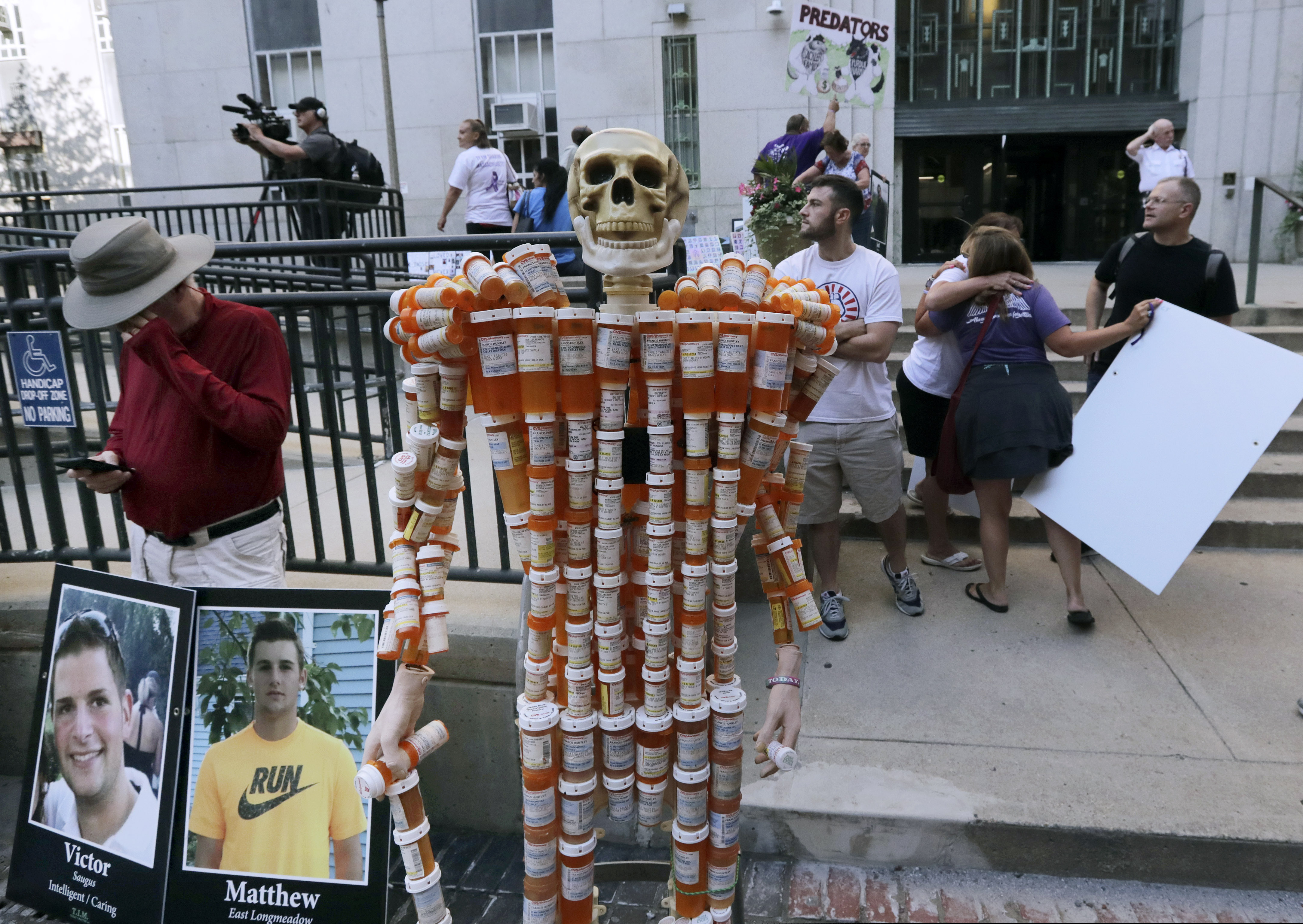 A skeleton of pill bottles stands with protesters outside a courthouse on Friday, Aug. 2, 2019, in Boston, where a judge was to hear arguments in Massachusetts' lawsuit against Purdue Pharma over its role in the national drug epidemic. Purdue executives discussed how they would combat an L.A. Times story online. (AP Photo/Charles Krupa)