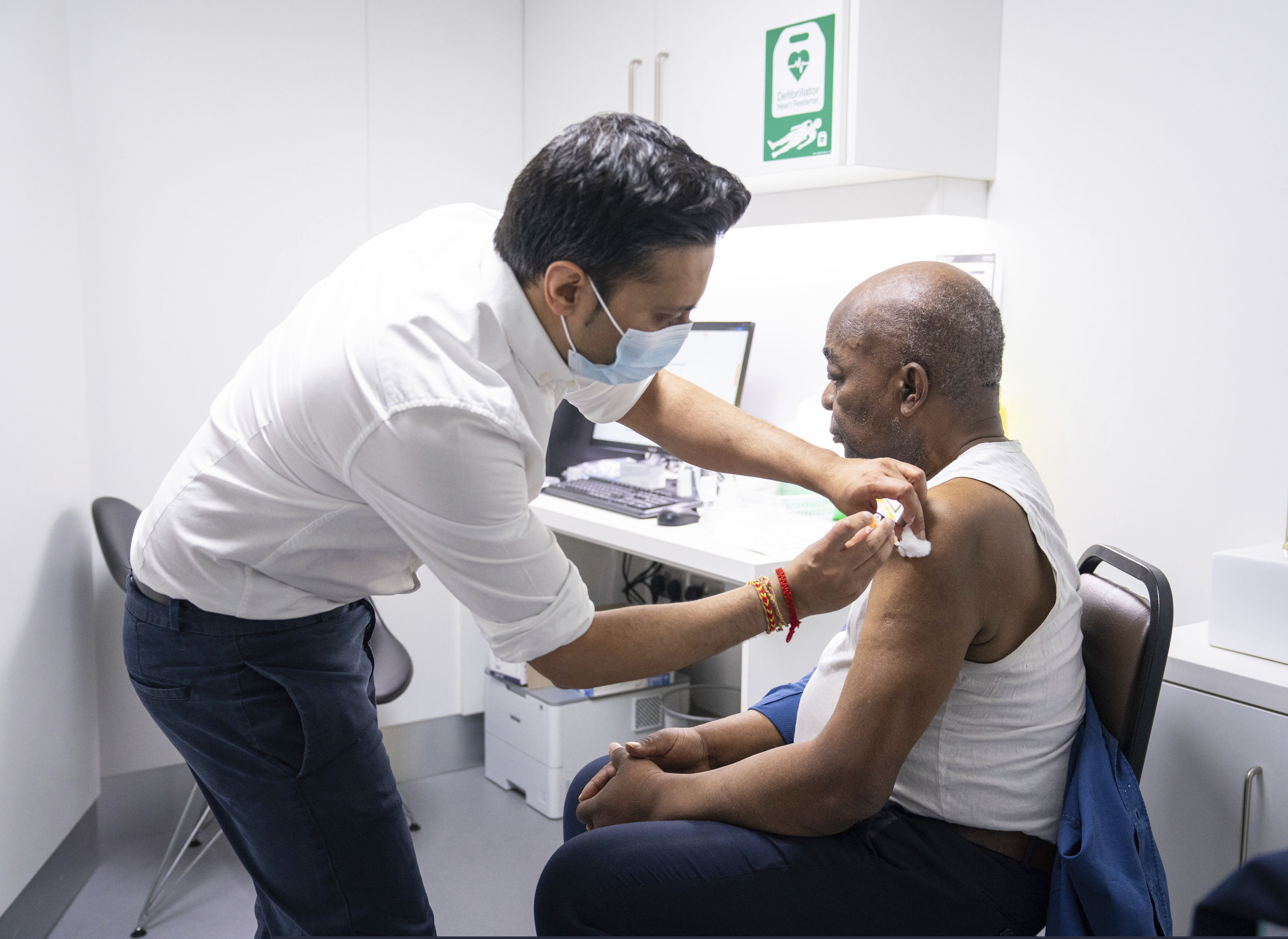 Pharmacist Bhaveen Patel administers a dose of the Oxford/AstraZeneca COVID-19 vaccine to Joshua Labor at a coronavirus vaccination clinic held at Junction Pharmacy in Brixton, London.