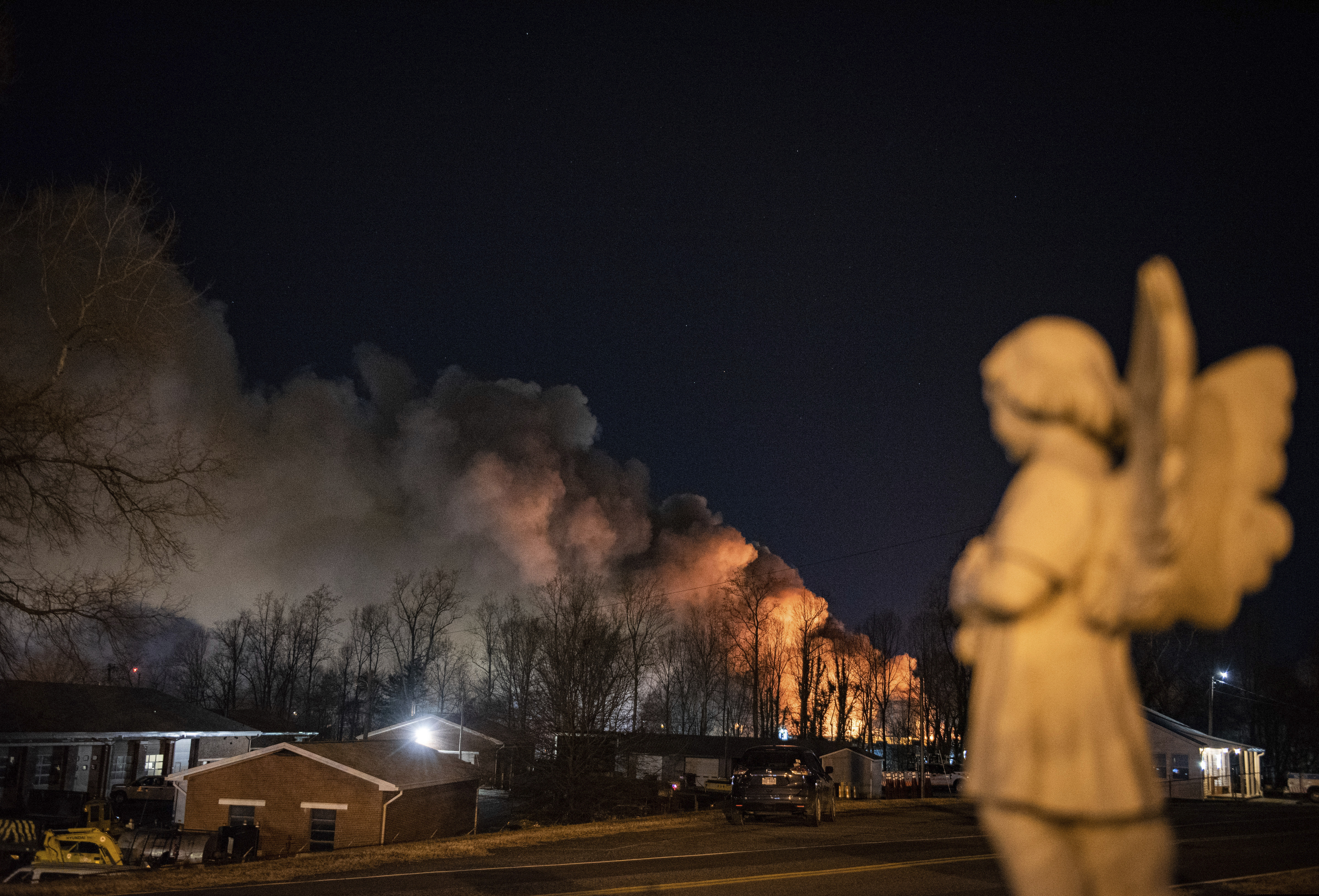 An angel statue faces in the direction of billowing smoke from a fire at the Weaver Fertilizer Plant on Monday night in Winston-Salem, N.C.
