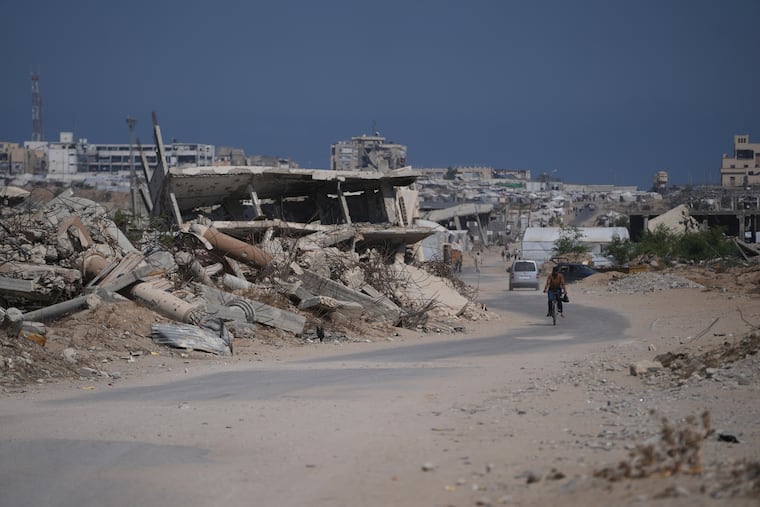 A Palestinian man rides his bicycle by the rubble of buildings that were destroyed during the Israel Hamas war, in Khan Younis, southern Gaza Strip, Friday, July 31, 2026.