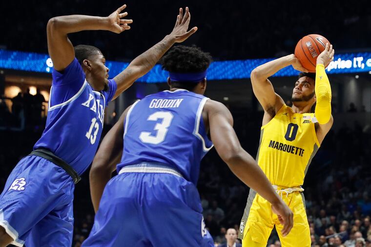 Marquette's Markus Howard (0) shoots against Xavier's Naji Marshall (13) and Quentin Goodin (3) in the second half of a game back on Jan. 26 in Cincinnati.
