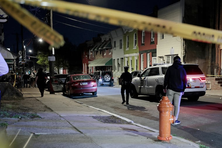The scene on 17th and Cumberland Streets in North Philly, where a police officer was shot in the leg on Monday while investigating the red car in front.