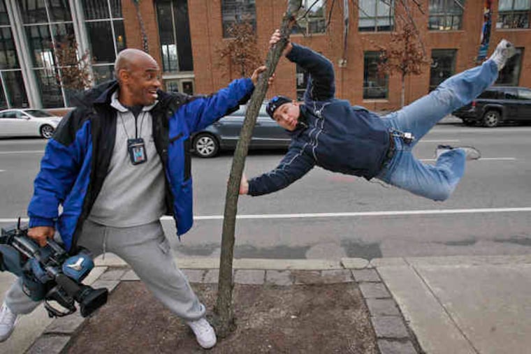 THE TREE WAS already bent when these two TV cameramen, Terry Gilmore (left), of 6 ABC, and Tom Gardiner, of CBS 3, decided to stage a joke picture to show how hard that wind was blowing yesterday.