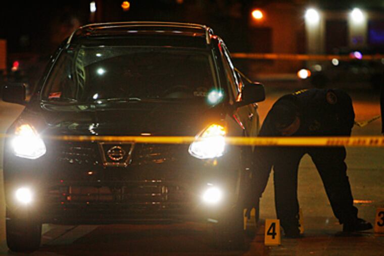 Philadelphia police mark evidence in a fatal shooting early this morning by an off-duty police officer outside the Electric Factory. The officer was in his SUV, pictured, when he says a man tried to rob him, authorities said. (ALEJANDRO A. ALVAREZ / Staff)