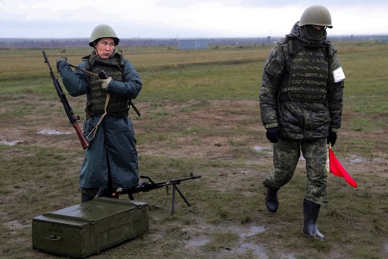 A recruit takes his weapons following an instructor during a military training at a firing range in Volgograd region, Russia, Thursday, Oct. 27, 2022.