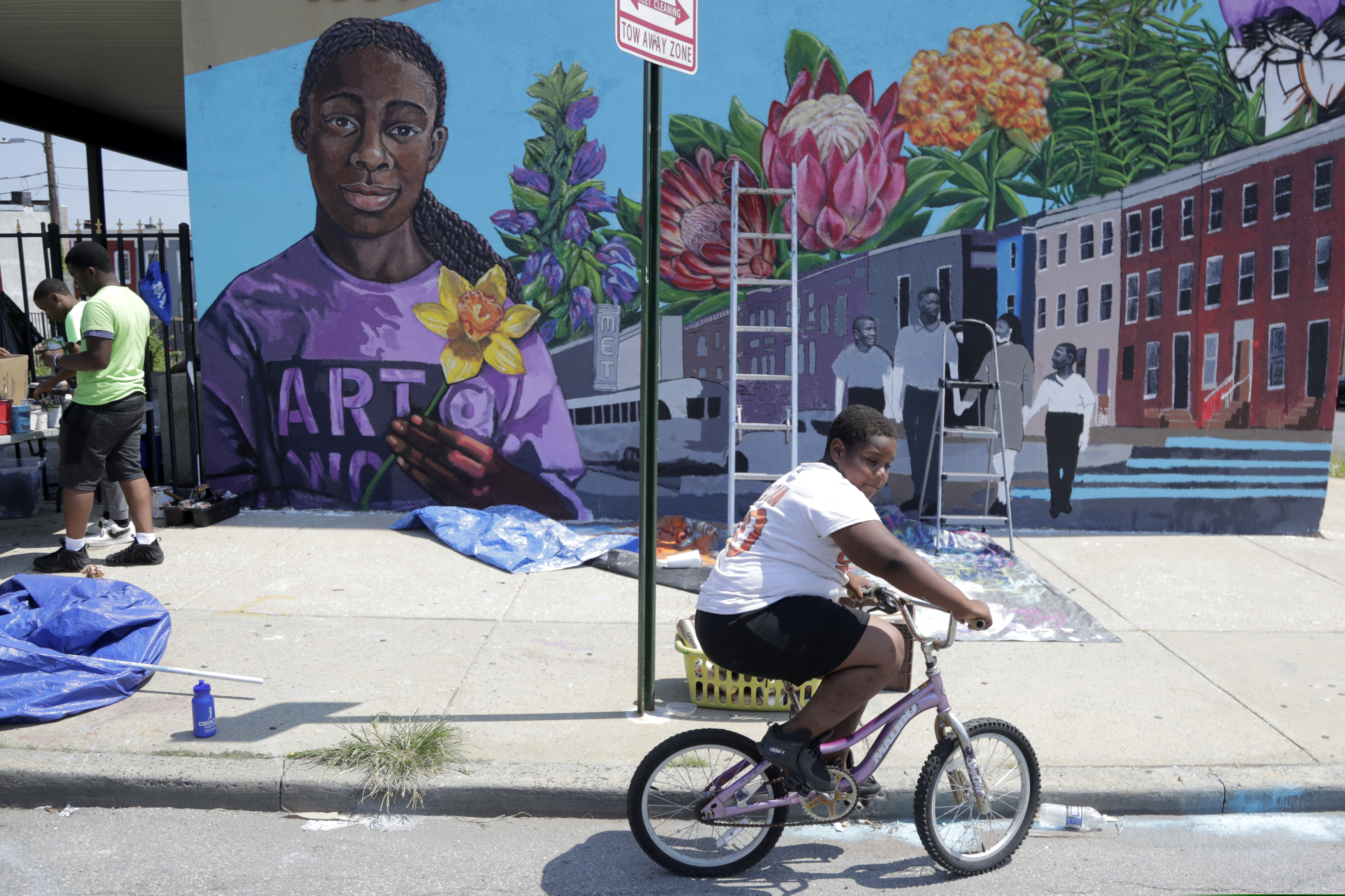A boy rides his bicycle Monday, July 29. 2019 after volunteering to paint a mural outside the New Song Community Church in the Sandtown section of Baltimore. In the latest rhetorical shot at lawmakers of color, President Donald Trump over the weekend vilified Rep. Elijah Cummings majority-black Baltimore district as a "disgusting, rat and rodent infested mess" where "no human being would want to live."