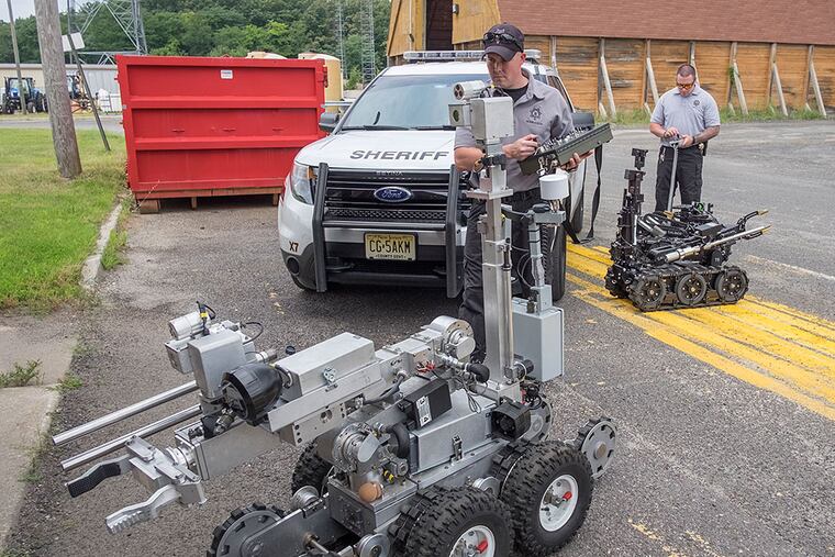 Joseph Welsh (left) and Neil Thorp, of the Camden County Sheriff’s Office bomb unit, with their robotic charges. ED HILLE / Staff Photographer