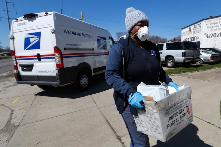 In this April file photo, a United States Postal Service worker makes a delivery with gloves and a mask in Warren, Mich. A group of states suing over service cuts at the U.S. Postal Service is asking a federal judge to immediately undo some of them, saying the integrity of the upcoming election is at stake.