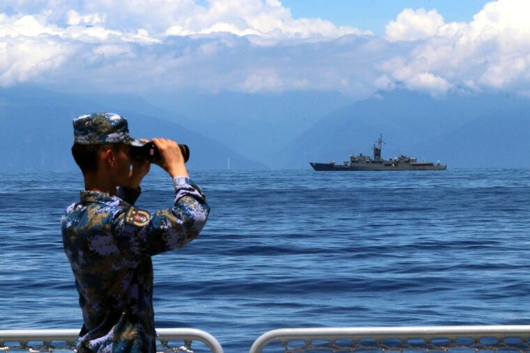 In this photo provided by China's Xinhua News Agency, a People's Liberation Army member looked through binoculars during military exercises as Taiwan's frigate Lan Yang was seen at the rear on Aug. 5.